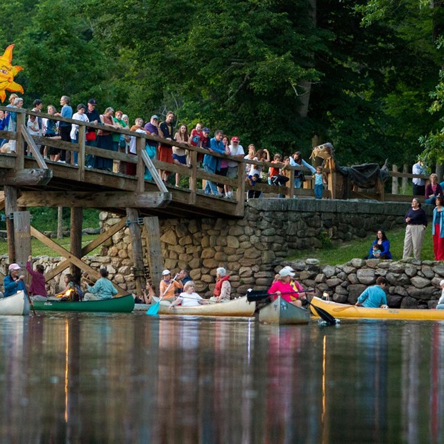 bridge over river with lots of people on it and canoes underneath